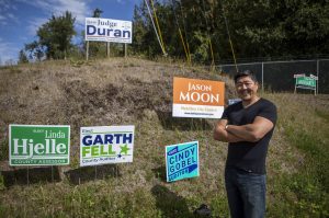 Mukilteo City Council member Jason Moon poses for a photo with his campaign sign along Mukilteo Speedway in Mukilteo, Washington, on Thursday, Sept. 7, 2023. (Annie Barker / The Herald)