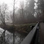 People bundled up in jackets and hats walk along the Sammamish River at Bothell Landing Park in Bothell, Washington on Tuesday, Nov. 28, 2023. Frost and colder temperatures have are prompting some Western Washington warming centers to open sooner than later. (Annie Barker / The Herald)