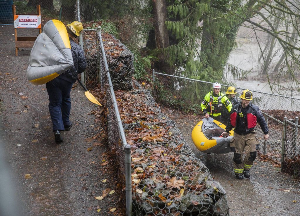 Snohomish Regional Fire and Rescue crews carry their inflatable rescue boat in Al Borlin Park on Tuesday, Dec. 5, 2023 in Monroe, Washington. (Olivia Vanni / The Herald)