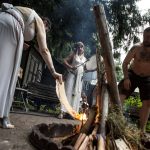 NMier LaVeau, left, and Jesse Sterland, right, start a fire for the Lammas and Wicker Man ritual while Mydnyte Windham, center, drums at the Aquarian Tabernacle Church in Index, Washington, in August 2023. (Annie Barker / The Herald)