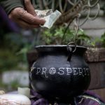 A Pagan donates to a cauldron labeled Prosperity at the Aquarian Tabernacle Church in Index, Washington, in August 2023. (Annie Barker / The Herald)