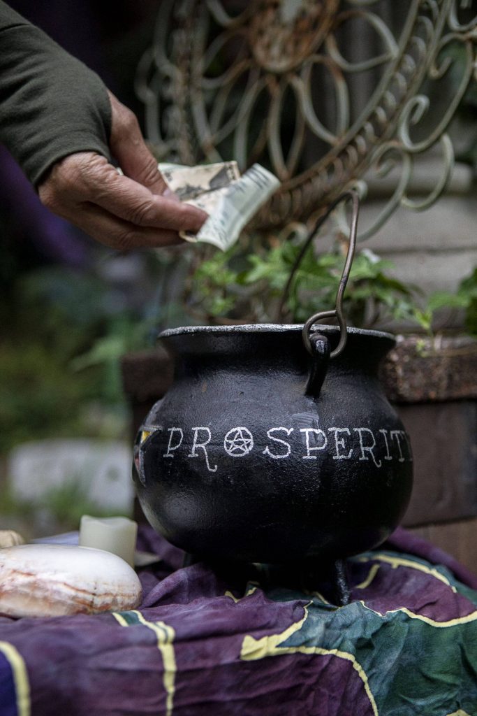 A Pagan donates to a cauldron labeled Prosperity at the Aquarian Tabernacle Church in Index, Washington, in August 2023. (Annie Barker / The Herald)