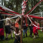 Titania ThunderLily, center, holds the maypole as Pagan revelers wrap red-and-white ribbon around it for a Beltane festival in May 2023, at the Aquarian Tabernacle Church in Index, Washington. Beltane celebrates the height of spring. (Annie Barker / The Herald)
