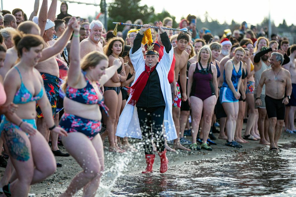 Edith Farrar watches as people begin to run into the ocean, perhaps a moment too early, during the 2023 Edmonds Polar Bear Plunge on Sunday, Jan. 1, 2023, at Bracketts Landing. The sea water was a chilly 47.7 degrees. (Ryan Berry / The Herald)