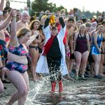 Edith Farrar watches as people begin to run into the ocean, perhaps a moment too early, during the 2023 Edmonds Polar Bear Plunge on Sunday, Jan. 1, 2023, at Bracketts Landing. The sea water was a chilly 47.7 degrees. (Ryan Berry / The Herald)