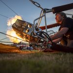 Erin Romaneschi, 33, fires up the burner and injects a hot air balloon with flames to heat the air inside during Kla Ha Ya Days at Harvey Field on Friday, July 14, 2023, in Snohomish, Washington. (Annie Barker / The Herald)