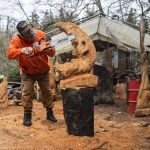 Steve Backus works on the details of a moon carving at his woodshop and home on Whidbey Island on Monday, Feb. 6, 2023. Steve Backus, a generational woodcarver, lost a portion of his shop to a fire. In the fire, he lost a large catalog of work, in addition to tools and other woodworking items he had accumulated over the years. (Olivia Vanni / The Herald)