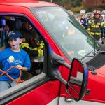 Carson, 7, reacts with shock as he gets an opportunity to use some of the gear inside an Everett ambulance during a surprise Make-a-Wish sendoff Saturday, Oct. 21, 2023, at Thornton A. Sullivan Park in Everett, Washington. Dozens of first responders, family and community members rallied together to lift up Carson before he and his family headed off to Disneyland. (Ryan Berry / The Herald)