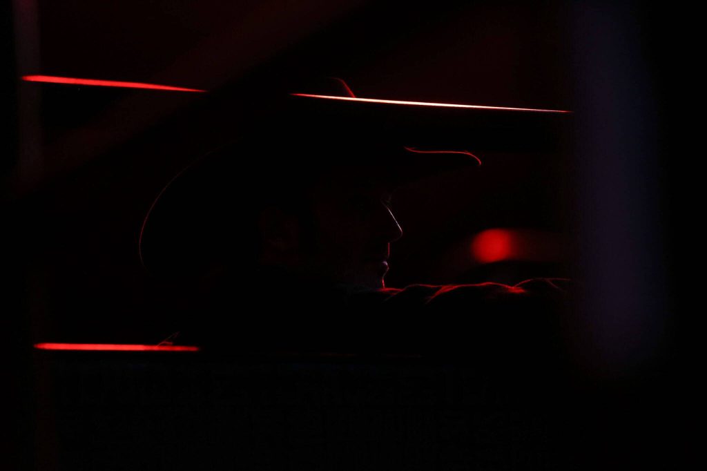 A man wearing a cowboy hat looks out into the arena during PBR: Unleash The Beast at Angel of the Winds Arena on Thursday, April 20, 2023, in Everett, Washington. (Annie Barker / The Herald)