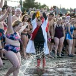 Edith Farrar watches as people begin to run into the ocean, perhaps a moment too early, during the 2023 Edmonds Polar Bear Plunge on Sunday, Jan. 1, 2023, at Brackett's Landing in Edmonds, Washington. The sea water was a chilly 47.7 degrees Fahrenheit on New Year's Day. (Ryan Berry / The Herald)