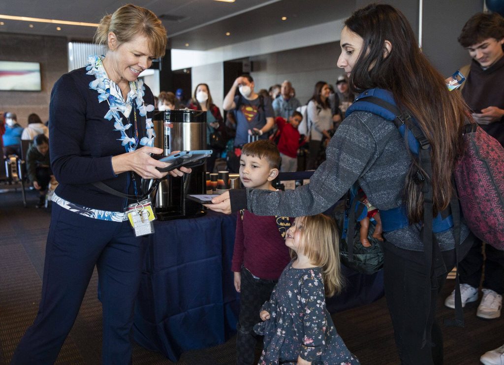 Katie Wallace, left, checks people into the first flight from Paine Field to Honolulu on Nov. 17, 2023 in Everett. (Olivia Vanni / The Herald)