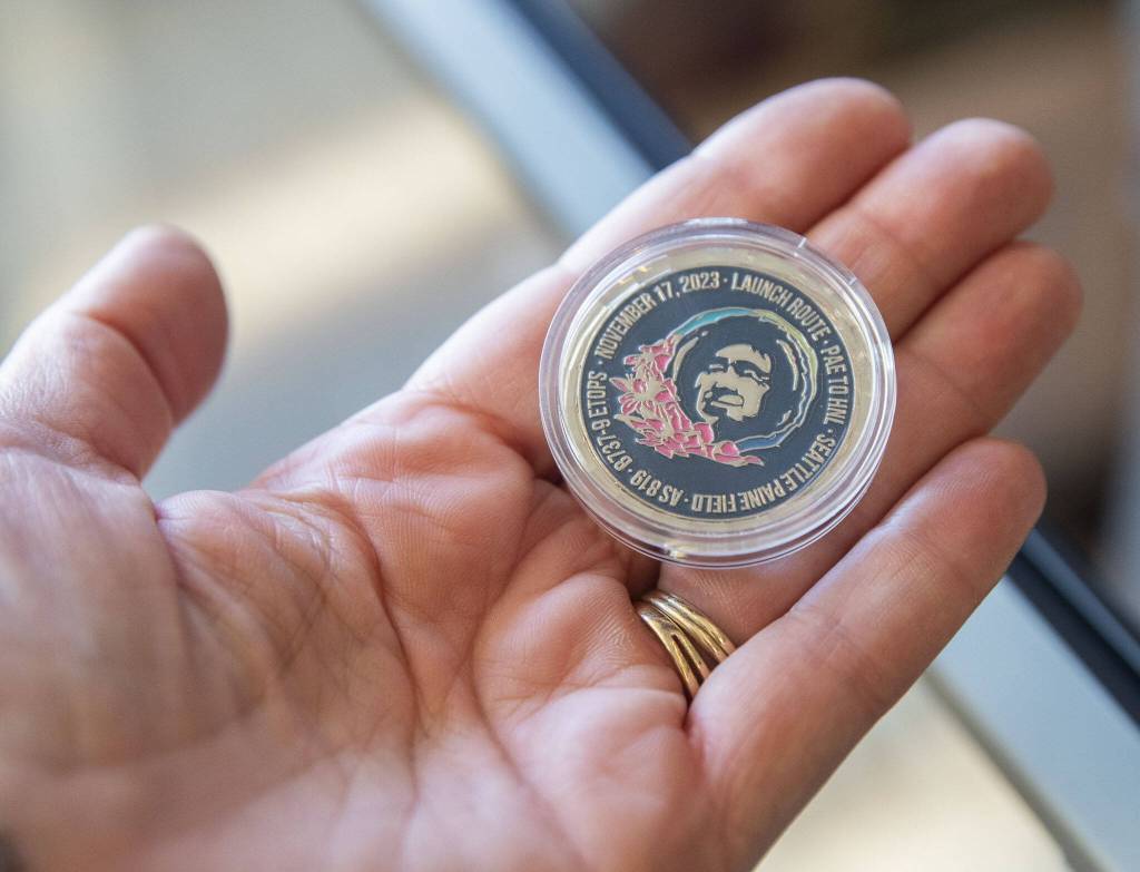 Coins commemorating the first flight from Paine Field to Honolulu are handed out to passengers on Nov. 17, 2023 in Everett, Washington. (Olivia Vanni / The Herald)