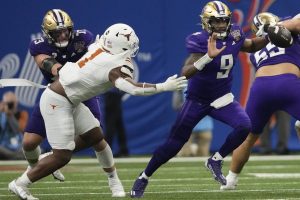 Washington quarterback Michael Penix Jr. (9) scrambles with the ball against Texas defensive end Justice Finkley (1) during the second half of the Sugar Bowl CFP NCAA semifinal college football game, Monday, Jan. 1, 2024, in New Orleans. (AP Photo/Gerald Herbert)