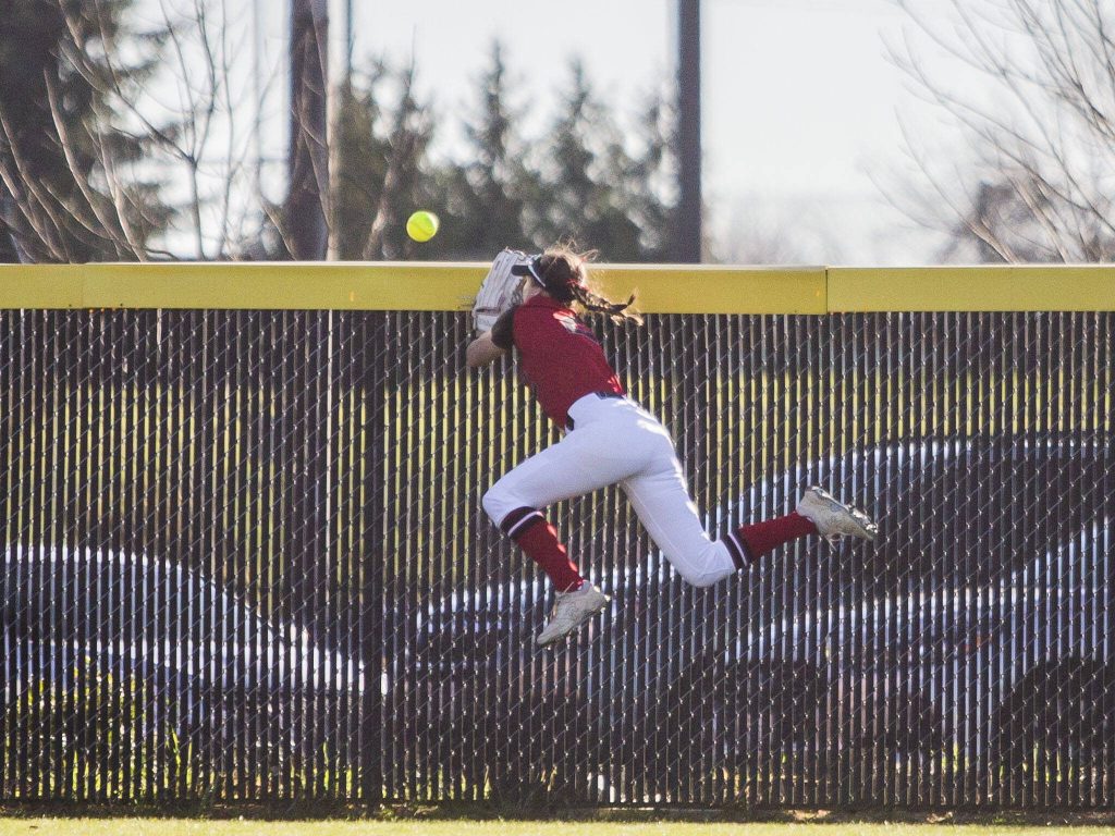Snohomishs Avery Clark leaps to try and catch a ball as it goes over the outfield fence during the game Glacier Peak on Friday, March 15, 2024 in Snohomish, Washington. (Olivia Vanni / The Herald)