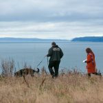 Pet detective Jim Branson and three-year-old Rafael the dog walk through an abandoned property with reporter Aina de Lapparent Alvarez while searching for Lyanna the cat on Saturday, March 2, 2024, in Everett, Washington. (Ryan Berry / The Herald)