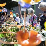 Nedra Vranish, left, and Karen Thordarson, right, browse colorful glass flowers at Fuse4U during Sorticulture on Friday, June 7, 2024, in Everett, Washington. (Olivia Vanni / The Herald)