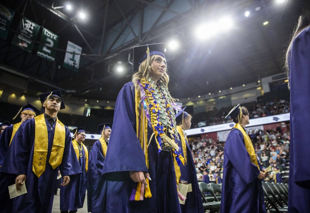 Gradutes walk down the center aisle to their seats during Arlington High School graduation at Angel of the Winds Arena on Thursday, June 13, 2024, in Everett, Washington. (Olivia Vanni / The Herald)
