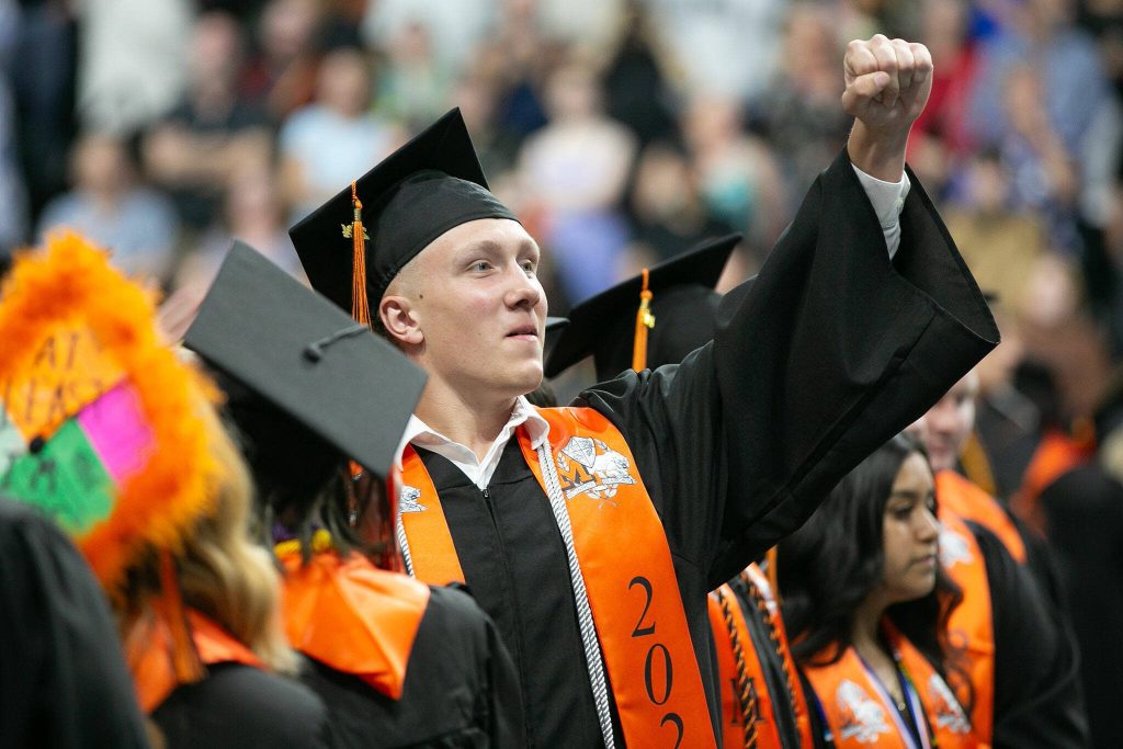 A graduate waves to the crowd in the stands during Monroe High Schools 2024 commencement on Wednesday, June 12, 2024, at Angel of the Winds Arena in Everett, Washington. (Ryan Berry / The Herald)
