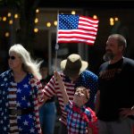 A young child holds up an American Flag during Everetts Fourth of July Parade on Thursday, July 4, 2024, in downtown Everett, Washington. (Ryan Berry / The Herald)