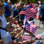 Members of the crowd wave flags during Everetts Fourth of July Parade on Thursday, July 4, 2024, in downtown Everett, Washington. (Ryan Berry / The Herald)