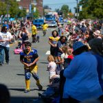 Players from Mariner Youth Football run around and distribute candy during Everetts Fourth of July Parade on Thursday, July 4, 2024, in downtown Everett, Washington. (Ryan Berry / The Herald)
