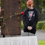 Natasha Atsatt, wearing a Never Forget shirt, takes a moment to read the names of those lost listed at the base of the 9/11 memorial built around a 1-ton beam recovered from the collapsed World Trade Center on Wednesday, Sept. 11, 2024, in Edmonds, Washington. (Olivia Vanni / The Herald)