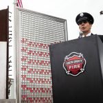 Retired South County Firefighter Dave Erickson speaks to a crowd of 50 people gathered outside of the Fallen Firefighter Memorial Park at the downtown Edmonds Fire Station on Wednesday, Sept. 11, 2024 for a 9/11 Memorial Ceremony. In the background of the ceremony stands a 1-ton beam recovered from the collapsed World Trade Center along with multicolored glass tiles. The tiles represent the more than 3,000 people killed, including 343 firefighters, 60 police and 10 emergency medical services workers. (Olivia Vanni / The Herald)