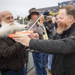 Bryan Nelson passes along a measuring tape for an official measurement during the Guinness World Record Beard Chain Attempt on Friday, Nov. 1, 2024 in Everett, Washington. (Olivia Vanni / The Herald)