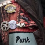 John Banks displays mustache and beard themed pins on his jean jacket during the Guinness World Record Beard Chain Attempt on Friday, Nov. 1, 2024 in Everett, Washington. (Olivia Vanni / The Herald)
