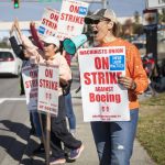 Jan James, a material processing specialist team lead who has been with Boeing for 22 years, uses a small megaphone to encourage drivers to honk in support of workers picketing along Airport Road on Tuesday, Oct. 1, 2024 in Everett, Washington. (Olivia Vanni / The Herald)