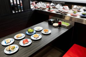 The conveyer belt moves past a table with a selection of food options available at Kura Sushi on Monday, April 7, 2025 in Lynnwood, Washington. (Olivia Vanni / The Herald)