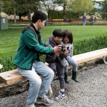 Peter Kwok, left, shows a photo to two of his children, Elliot and Rylan Kwok, at Roozengaarde outside of Mount Vernon, Washington during the Skagit Valley Tulip Festival on April 10, 2025. (Will Geschke / The Herald)