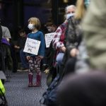 Juniper Player, 4, a student at the Early Learning Center, wears a sign in protest of the proposed plan to close pre-kindergarten facility on Tuesday, Nov. 30, 2021 in Everett, Wa. (Olivia Vanni / The Herald)