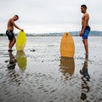 Ellis Johnson, 16, left, and brother Garrett Johnson, 13, take a breather after trying to find enough water to skim board on without sinking into the sand during opening day of Jetty Island on Friday, July 5, 2019 in Everett, Wash. (Olivia Vanni / The Herald)