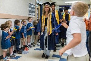 Everett High School graduate Gwen Bundy high fives students at her former grade school Whittier Elementary during their grad walk on Thursday, June 12, 2018 in Everett, Wa. (Olivia Vanni / The Herald)