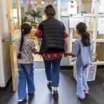 Preschool teacher Michelle Depew walks hand in hand with former Early Learning Center students Lareen Almadjidi, 7, left, and Qamar Almadjidi, 9, right, as they explore their old classroom on Wednesday, June 25, 2025 in Everett, Washington. (Olivia Vanni / The Herald)