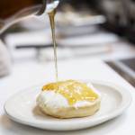Honey is poured of over ricotta before a sprinkle of walnuts while assembling The Walrus crumpet on Tuesday, June 24, 2025 in Edmonds, Washington. (Olivia Vanni / The Herald)