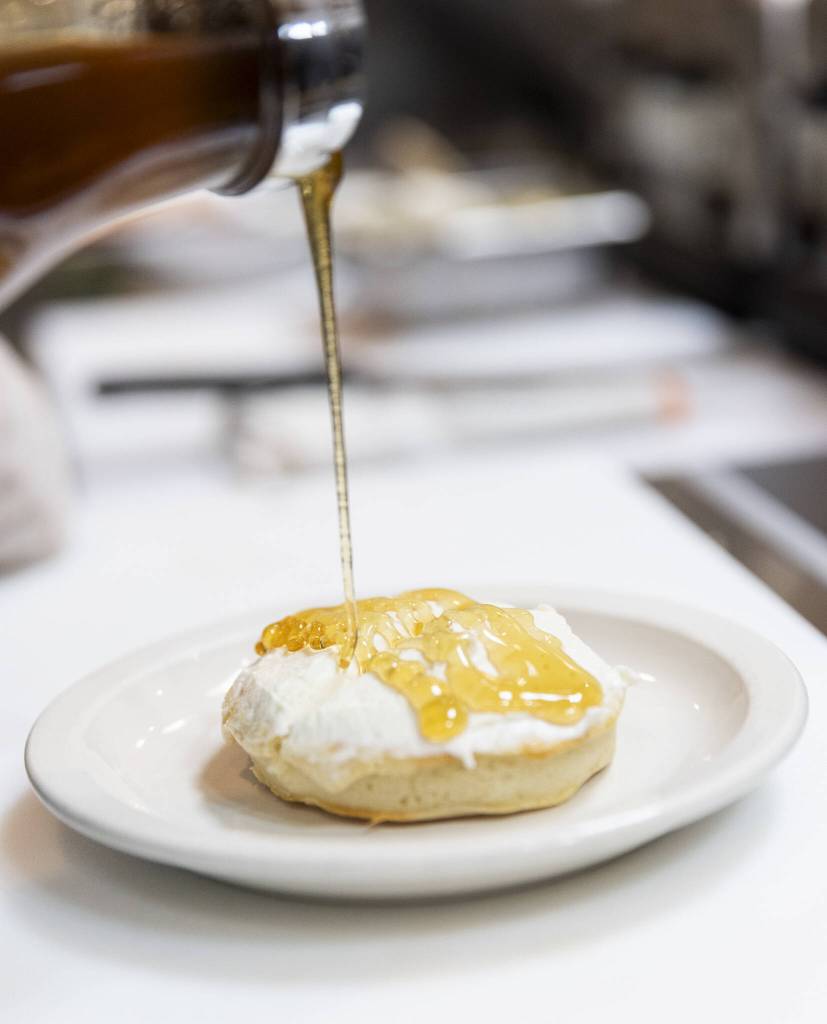 Honey is poured of over ricotta before a sprinkle of walnuts while assembling The Walrus crumpet on Tuesday, June 24, 2025 in Edmonds, Washington. (Olivia Vanni / The Herald)