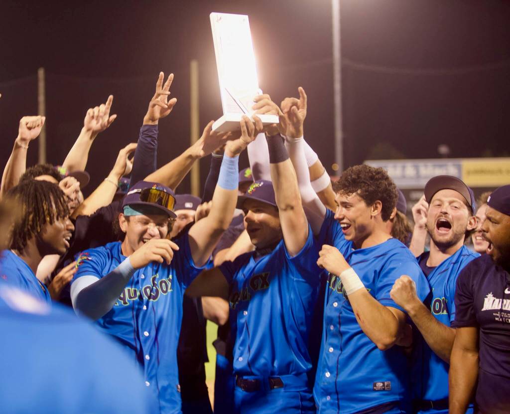 AquaSox infielders Luis Suisbel (center, left) and Charlie Pagliarini (center, right) hoist the Northwest League Championship trophy as teammates celebrate around them following Everetts series-clinching 6-3 win in Game 4 against the Eugene Emeralds at Funko Field on Sept. 13, 2025. (Joe Pohoryles / The Herald)