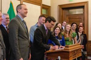 Gov. Bob Ferguson signing Senate Bill 5480, a bill exempting medical debt from credit reports, on April 22. (Photo by Jacquelyn Jimenez Romero/Washington State Standard)