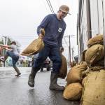 Zach Day sandbags the entrance to his grandparents residence along Main Street on Wednesday, Dec. 10, 2025 in Sultan, Washington. (Olivia Vanni / The Herald)