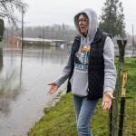 Sheryl Farmer stands in front of her home along Second Street as floodwater from the Skykomish River covers the road on Wednesday, Dec. 10, 2025 in Sultan, Washington. (Olivia Vanni / The Herald)