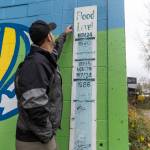 Ken Cradduck and his son Jedi, 10, look at the historic flood level markings at the base of a building along the Snohomish River Trail on Tuesday, Dec. 9, 2025 in Snohomish, Washington. (Olivia Vanni / The Herald)