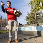 Brandon Tepley does a signature Butch pose while holding a vintage Butch head outside of his job at Mukilteo Elementary where he is dean of students on Thursday, Jan. 22, 2026 in Mukilteo, Washington. (Olivia Vanni / The Herald)