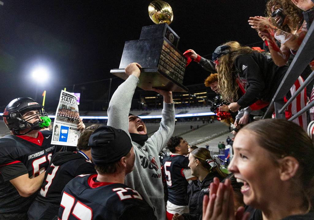 Archbishop Murphys Tayden Olson holds up the 2A state championship trophy to the Archbishop Murphy student section at Husky Stadium on Saturday, Dec. 6, 2025, in Seattle, Washington. (Olivia Vanni / The Herald)