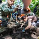 Josh Thiel, left, places a nail into a dust pan while Rey Wall continues digging in a sectioned-off piece of land at Japanese Gulch on Wednesday, July 23, 2025, in Everett, Washington. (Olivia Vanni / The Herald)