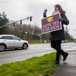 Jaime Benedict, who works as a substitute teacher, waves to drivers on the corner of Mukilteo Speedway and Harbor Pointe Boulevard while holding a sign in support of the $240 million capital bond proposal for Mukilteo School District on Tuesday, Feb. 11, 2020 in Mukilteo, Wash. (Olivia Vanni / The Herald)