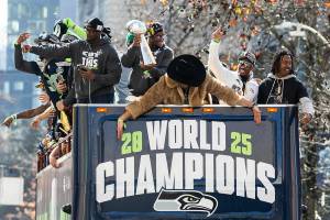 Seattle Seahawks’ Kenneth Walker III holds the Lombardi Trophy and other players cheer as one of their buses makes its way up 4th Avenue during their World Champions Parade on Wednesday, Feb. 11, 2026 in Seattle, Washington. (Olivia Vanni / The Herald)