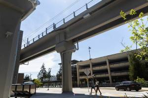 People walk under the Mountlake Terrace Station light rail tracks on Wednesday, July 30, 2025 in Mountlake Terrace, Washington. (Olivia Vanni / The Herald)