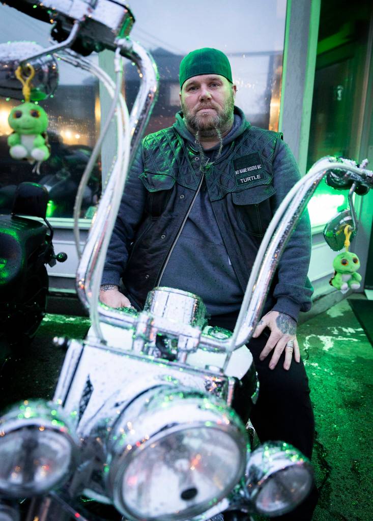 Jeff Turtle Ginnard sits on his bike that has two turtle plushies hanging of the handlebars on March 12, 2026, in Everett. (Olivia Vanni / The Herald)